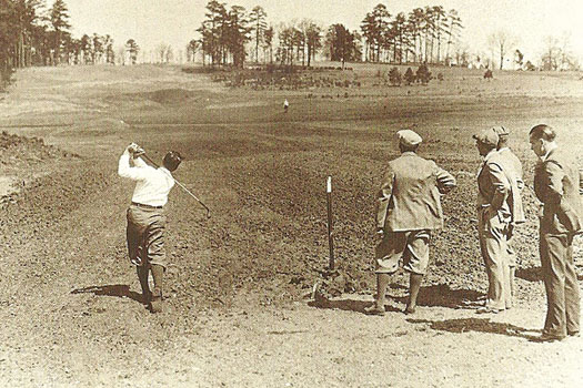 Bobby Jones hits a tee shot at the eighth hole at Augusta National during the construction phase as MacKenzie looks on