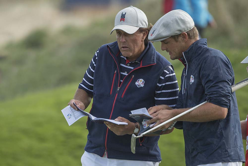 Phil Mickelson and Bryson Dechambeau compare notes on a green