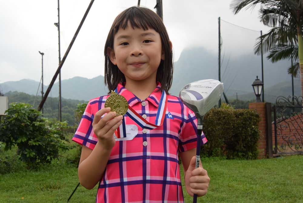 7-year-old Athena Chan shows off her gold medal and newly-won driver